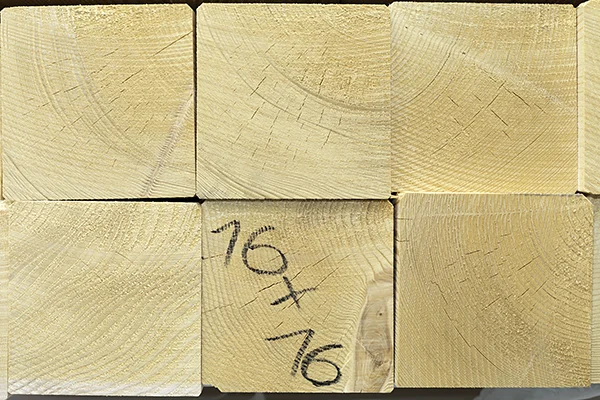 Czoła belek konstrukcyjnych KVH w stosie, na jednej odręczny zapis wymiaru 16x16
