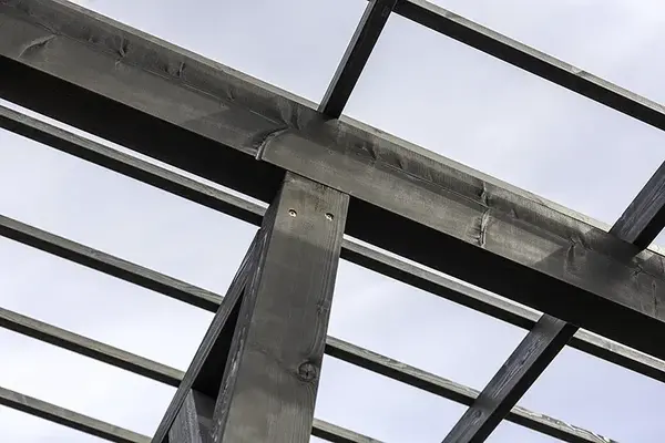 Widziana od dołu pozioma belka nośna z ciemnego drewna, na której opierają się poprzeczne krokwie